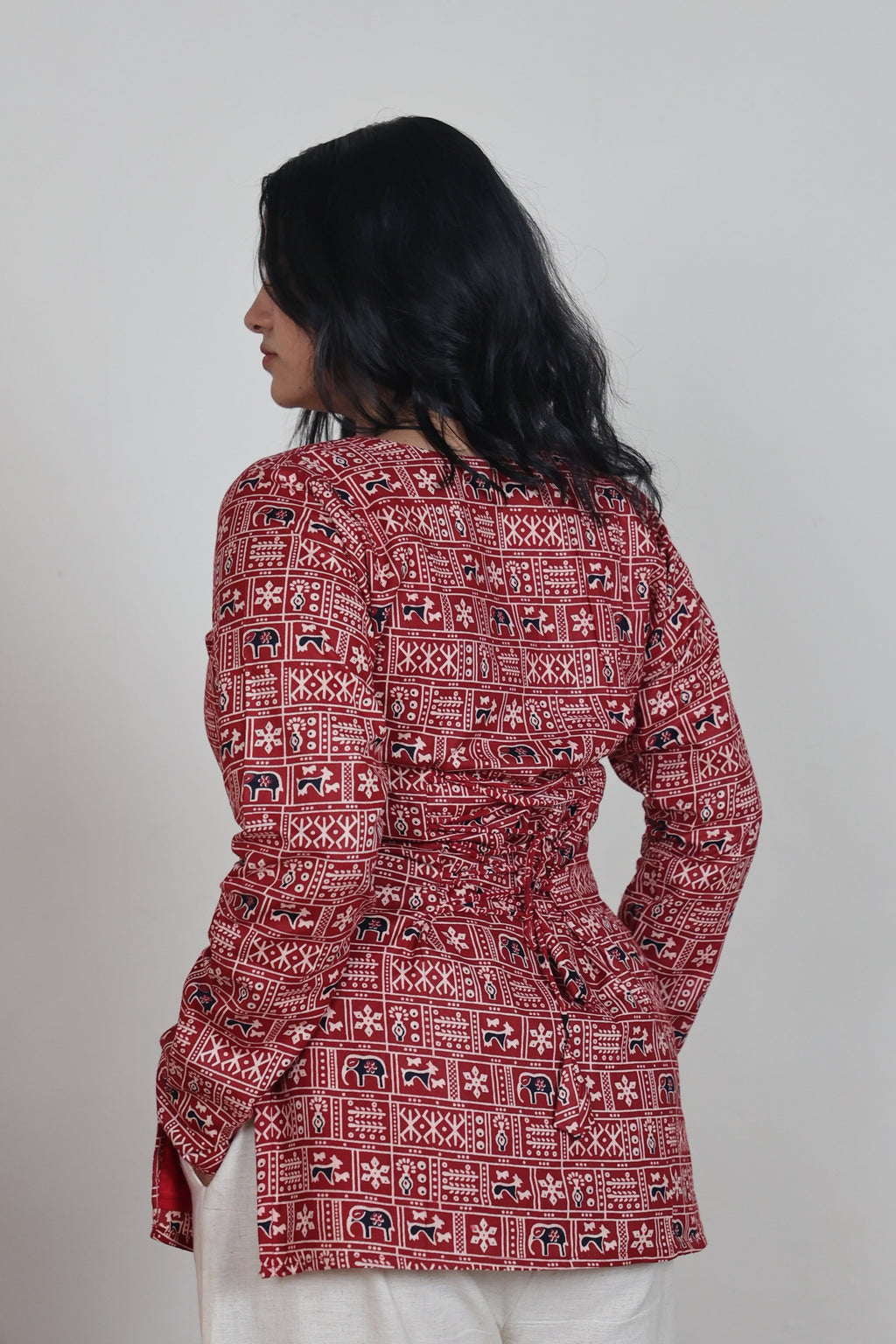 Person wearing a red patterned outfit on a plain background