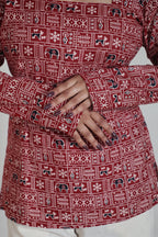 Red patterned garment with a person's hand visible, sitting on a white surface.