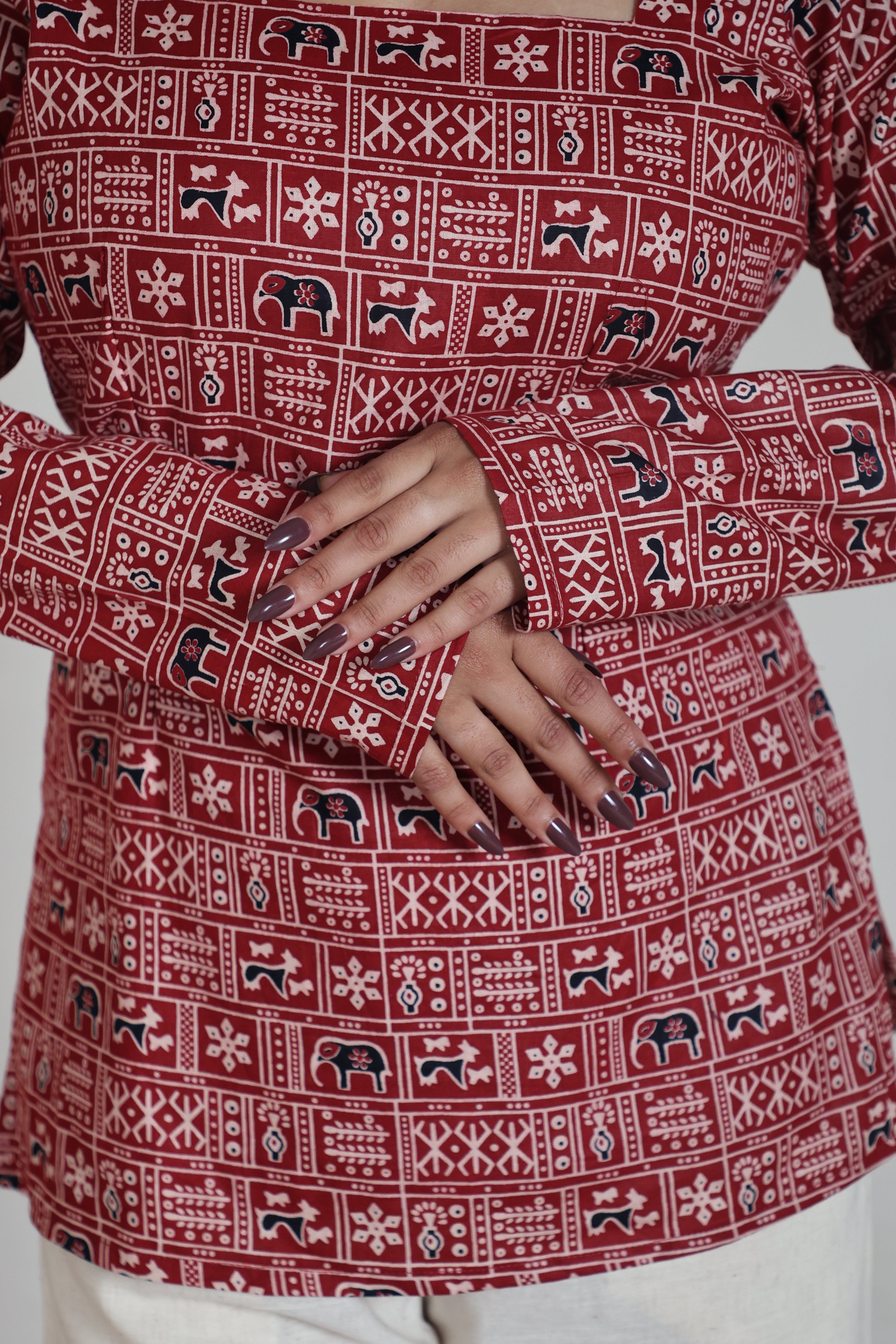 Red patterned garment with a person's hand visible, sitting on a white surface.