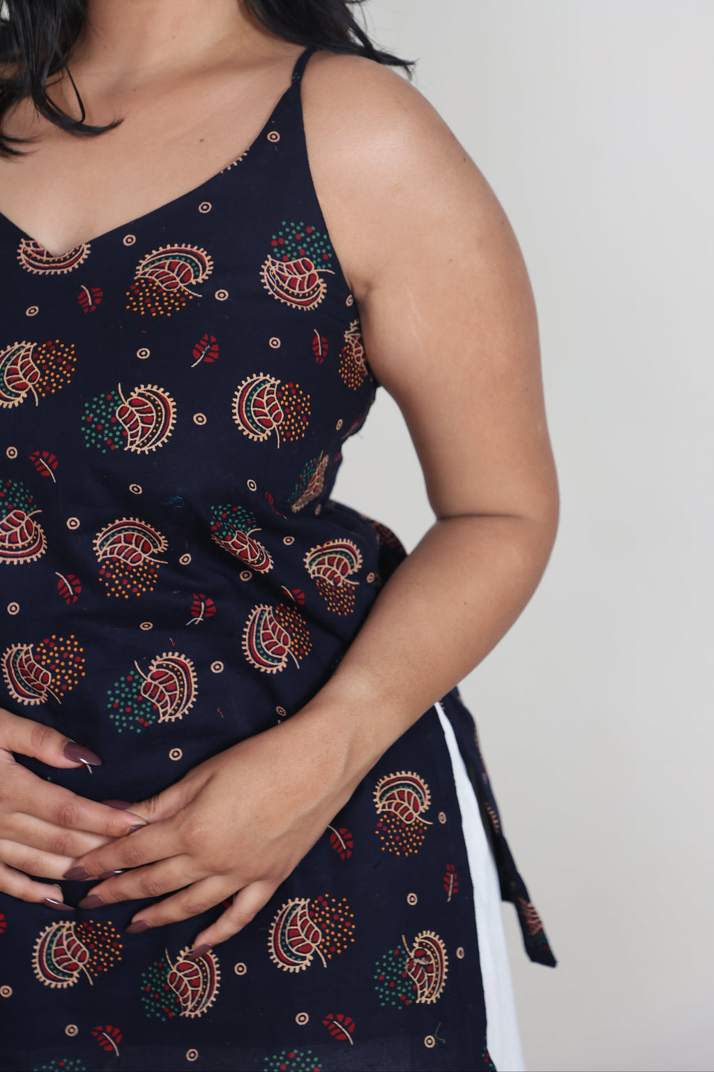 Woman wearing a dark blue dress with colorful patterns on a white background