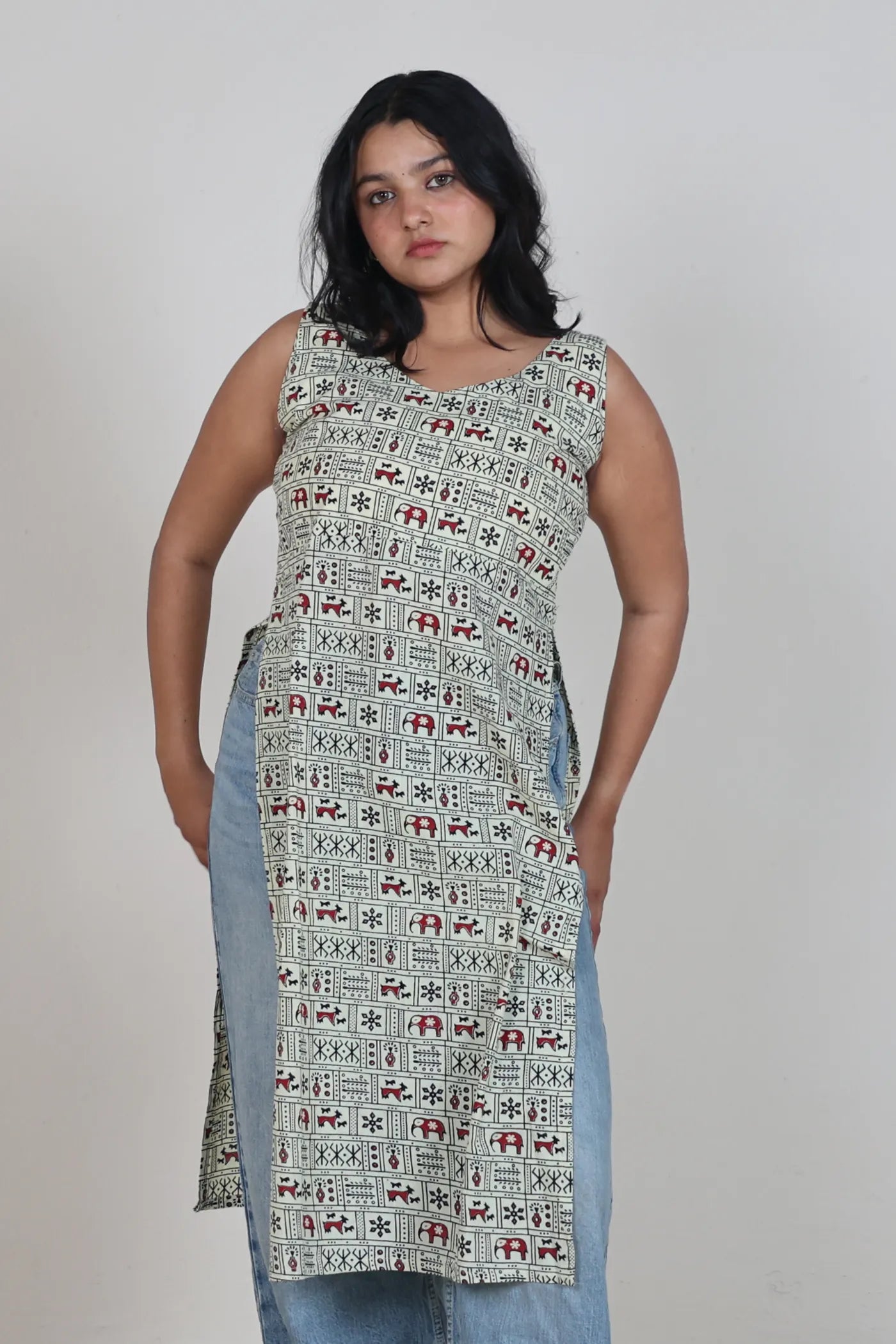 Woman wearing a sleeveless patterned kurti with a plain background