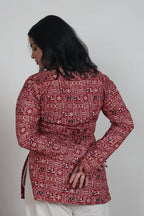 Woman wearing a red patterned kurti against a plain background