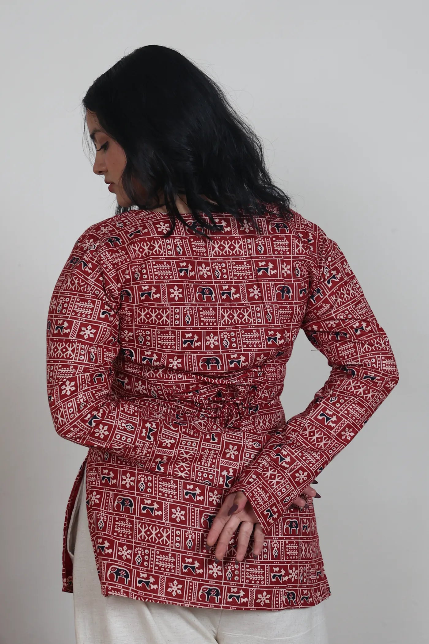 Woman wearing a red patterned kurti against a plain background